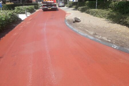 Reinigen van vervuild rood asfalt met wegdekreiniger met drugsafval.jpg